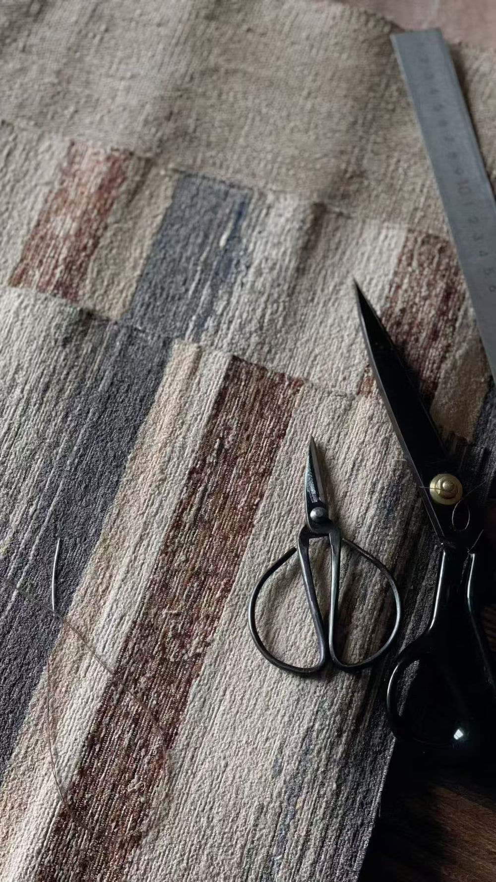 Striped woven cloth with a pair of black scissors and a metal ruler on it.
