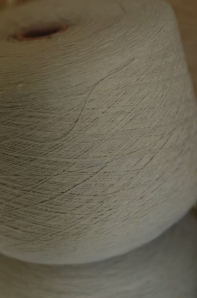 A cone of undyed white yarn.