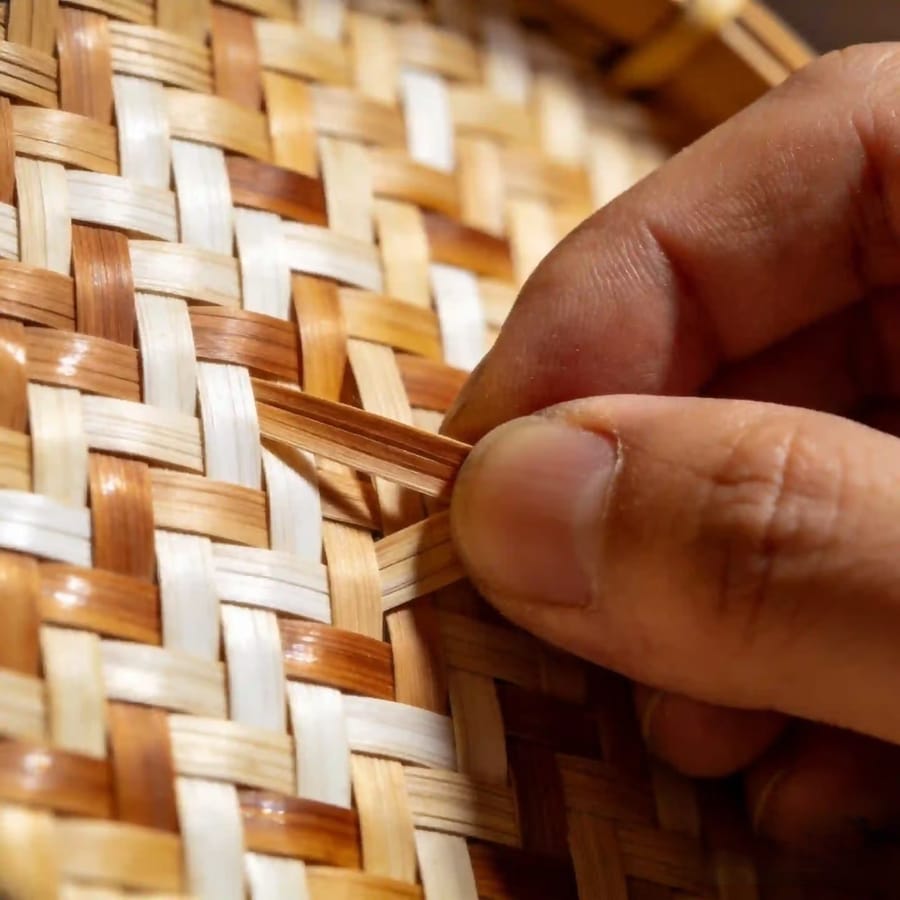 Close-up of hands weaving bamboo strips by hand